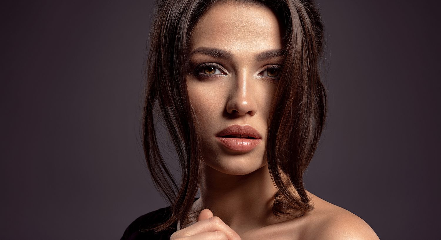Woman with short hair posing against dark background.